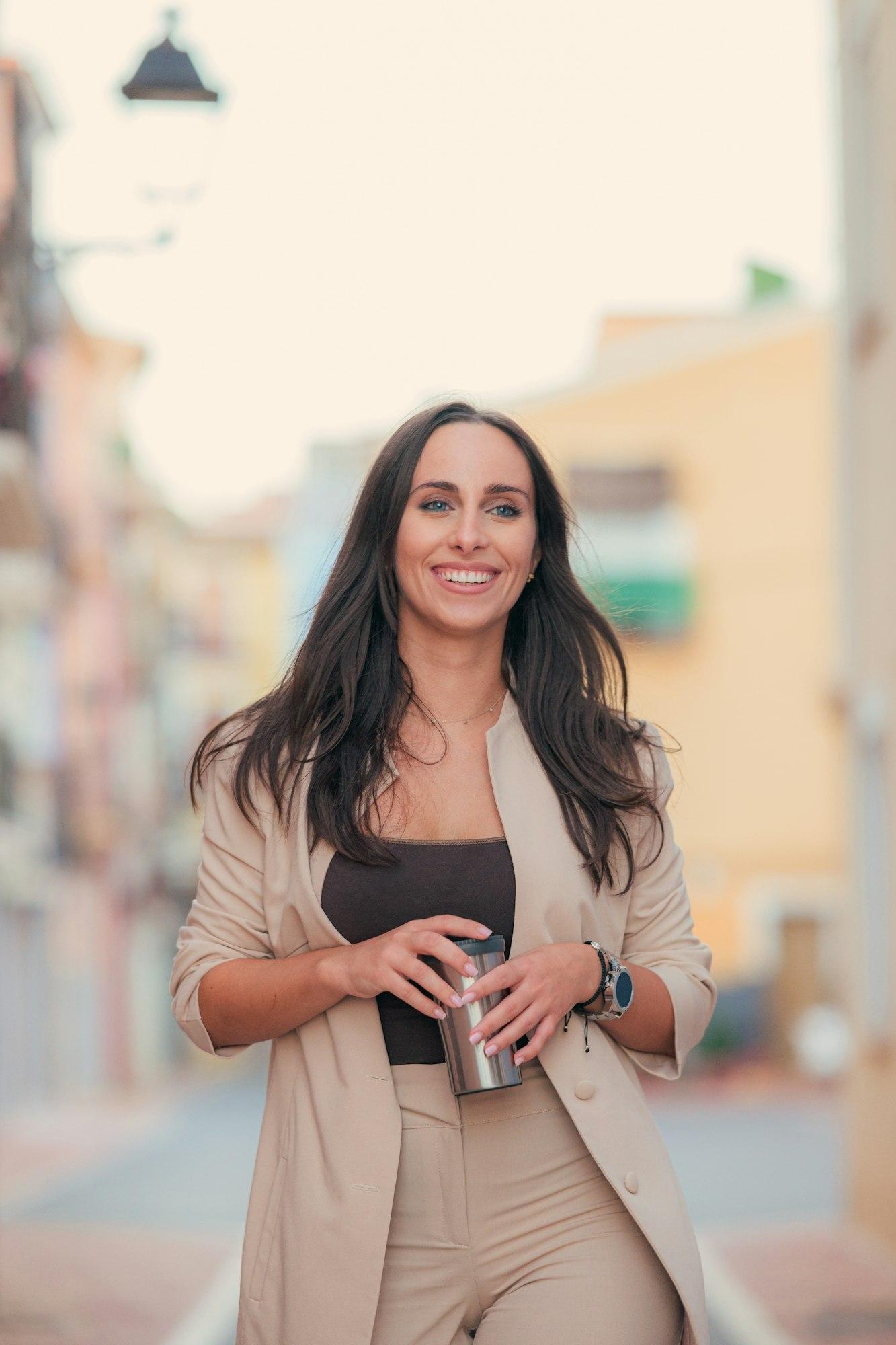 Happy business woman walking on the street with a coffee